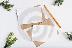 Two Christmas blank greeting cards mock up, top view. Craft envelopes, pine twigs, pencil and cards with empty space for text