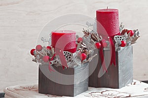 Two Christmas floral decorations with red candles