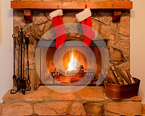 Two Christmas stockings on the mantle of a stone fireplace with a warm fire. photo
