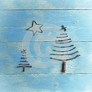 Two Christmas trees and star made from dry sticks on wooden, blue background. Christmas tree ornament, craft