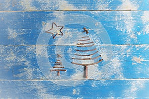 Two Christmas trees and star made from dry sticks on wooden, blue background. Christmas tree ornament, craft.