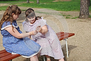 Two chubby young girls met in a park on a bench