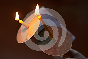 Two church candles and a sheet of prayer in the hand on a dark background