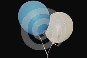 Two circle balloons in white and blue colours on night sky background with white ribbons. Birthday party outdoor.