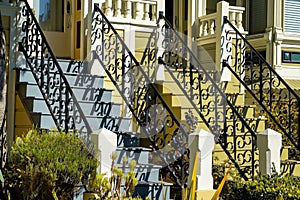 Two classic front door stair cases with visible stoops and front porch with black hand rails and blue and yellow color