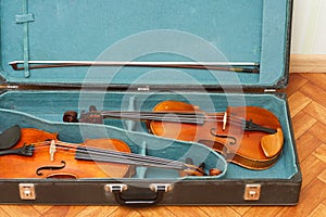 Two classical violins with bows in a double case