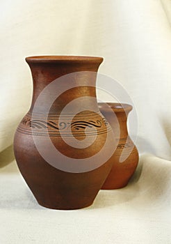 Two clay pots on the background of linen cloth with pleats close up