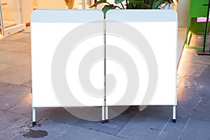 Two clear street signage boards placed by an outdoor dinning area of a restaurant.