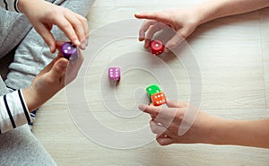 Two clever children study mathematics playing with dices on the floor