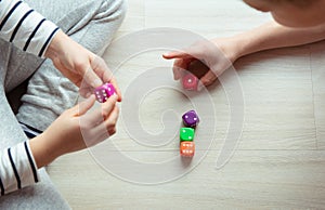 Two clever children study mathematics playing with dices on the floor