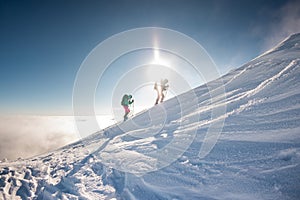 two climbers climb the mountain. Two girls climb a snow-covered mountain