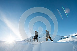 Two climbers with an ice ax walking in the snowy mountains.