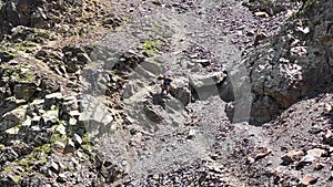 Two climbers with large backpacks descend from a high mountain, holding on to the ropes.