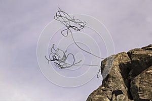 Two climbing ropes thrown over rock cliff twisting and unfurling in the air