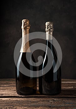 Two closed bottles of alcohol on a dark wooden background.