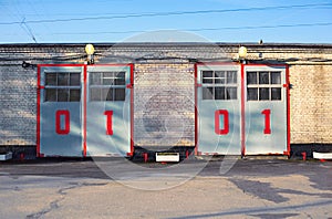 Two closed wide gates of the fire station with large bright red numbers 01 on them