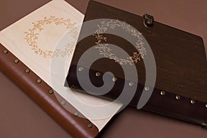 Two closed wooden wedding books with embossing. Dark and light wooden notebooks. Close up. Wedding photobook
