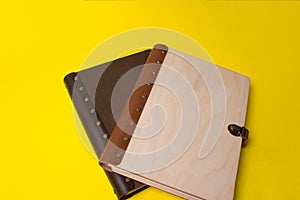 Two closed wooden wedding books on yellow colored paper background. Dark and light wooden notebooks. Close up. Wedding photobook