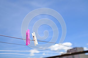 Two clothespin pink and white on a clothesline  on a sunny blue sky