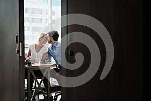 Two Co-Workers Sitting At Office Desk And Kissing