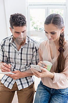 Two co-workers smiling while watching a video on the mobile in a