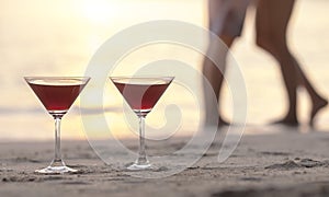 Two cocktails on the beach with couple kissing in background