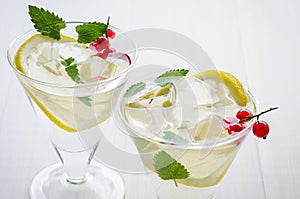 two cocktails with mint and ice on a white background/two cocktails with mint and ice on a white wooden background