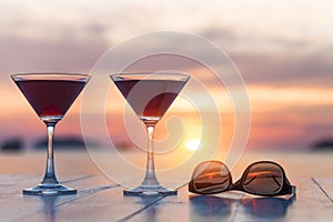 Two cocktails and sunglasses at a beach restaurant, honeymoon, sunset