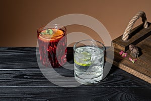 Two coctails on a wooden table near a tray, one Negroni other Caipirinha, traditional Brazilian alcoholic drink, typical