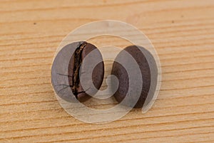 Two coffee beans in differen positions on wooden table