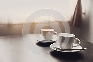 Two coffee cups on table at windows morning