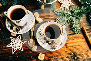 Two cups of espresso with pieces of cane sugar and Italian coffee maker on wooden table.