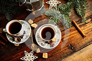 Two cups of espresso with pieces of cane sugar and Italian coffee maker on wooden table.