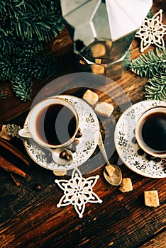 Two cups of espresso with pieces of cane sugar and Italian coffee maker on wooden table.