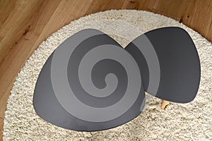 Two coffee tables stand on a round rug, the top view. Living room interior fragment