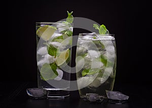 Two cold mojito cocktails on a dark background