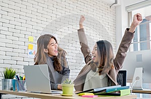 Two colleague businesswoman arms up for good news from job on la