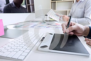 Two colleague creative graphic designer working on color selection and color swatches, drawing on graphics tablet at workplace