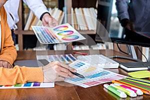 Two colleague creative graphic designer working on color selection and color swatches, drawing on graphics tablet at workplace