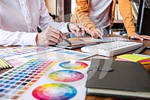 Two colleagues creative graphic designer working on color selection and drawing on graphics tablet at workplace