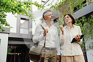 Two colleagues discussing business details and using tablet while standing outdoors