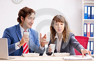 Two colleagues having lunch break at workplace