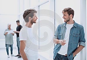 Two colleagues talking standing in the office corridor