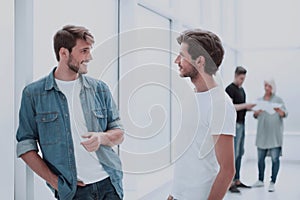 Two colleagues talking standing in the office corridor