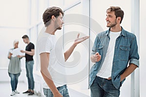 Two colleagues talking standing in the office corridor