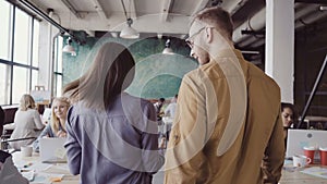 Two colleagues walking through and discussing the documents. Asian woman and caucasian man working at modern office.