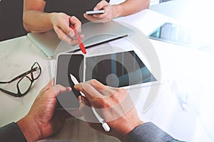 two colleagues website designer discussing data and digital tablet and computer laptop and smart phone on marble desk as