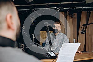 Two college podcasters laughing and having a good time in a studio. Two happy young men co-hosting a live audio