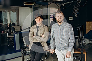 Two college podcasters laughing and having a good time in a studio. Two happy young men co-hosting a live audio