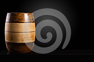 Two-color wooden barrel on black table and dark background, copy space